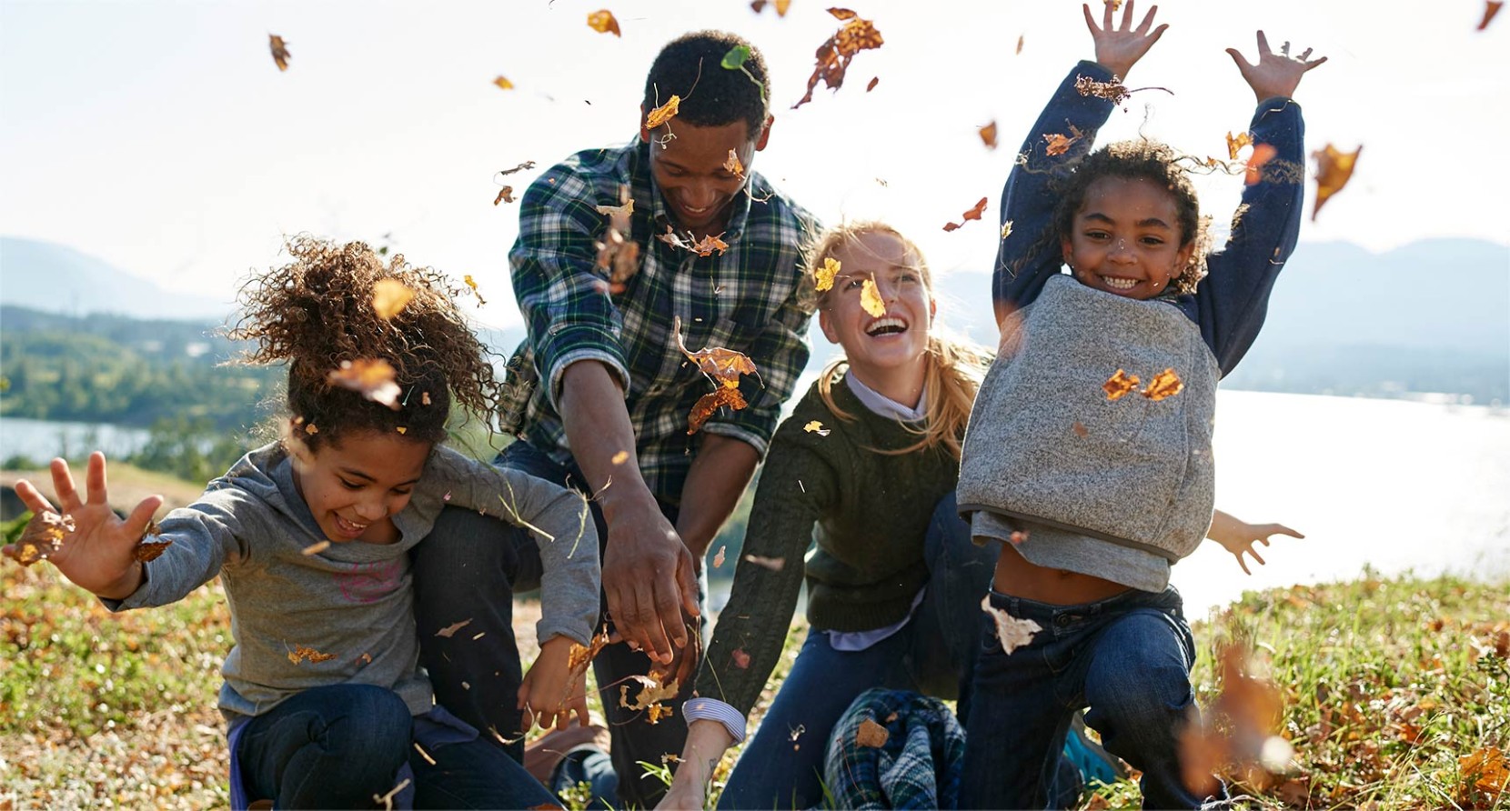 Image of happy family in L.L.Bean clothes throwing leaves in the air.