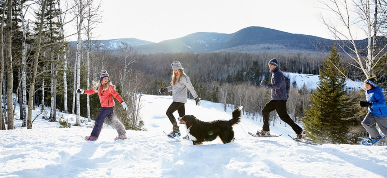 family snowshoeing with dog