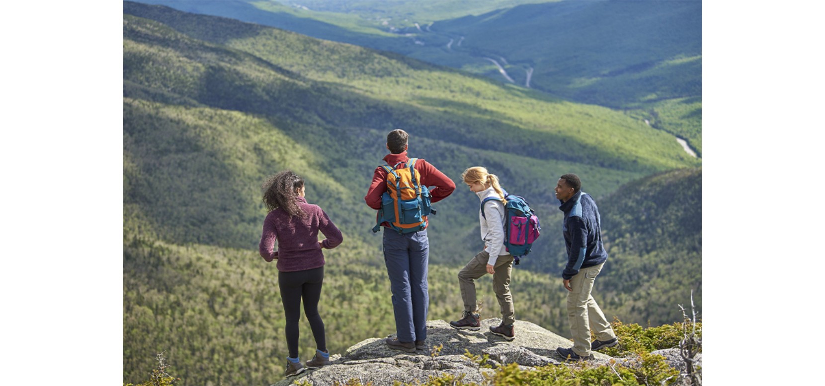 4 people standing on a mountaintop enjoying the view.