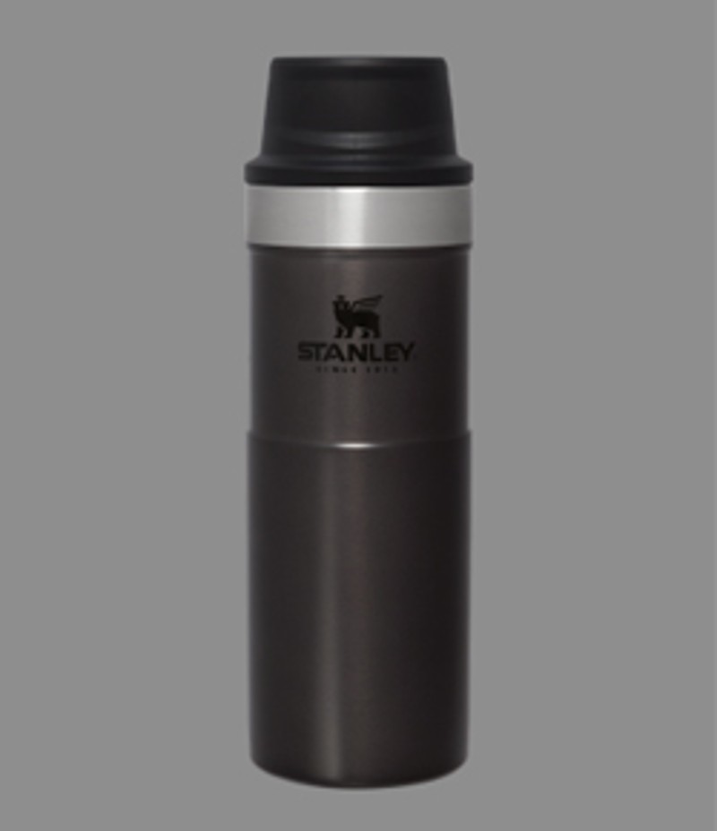 A black Stanley 1913 Trigger Action Travel Mug on a gray background